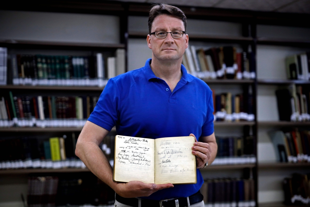 German archivist Stefan Litt displays a guestbook of Moshe Yaakov Ben-Gavriel, bearing the signature of SS officer Leopold von Mildenstein, at the Jerusalem National Library on May 1, 2019.  AFP / Thomas Coex
 