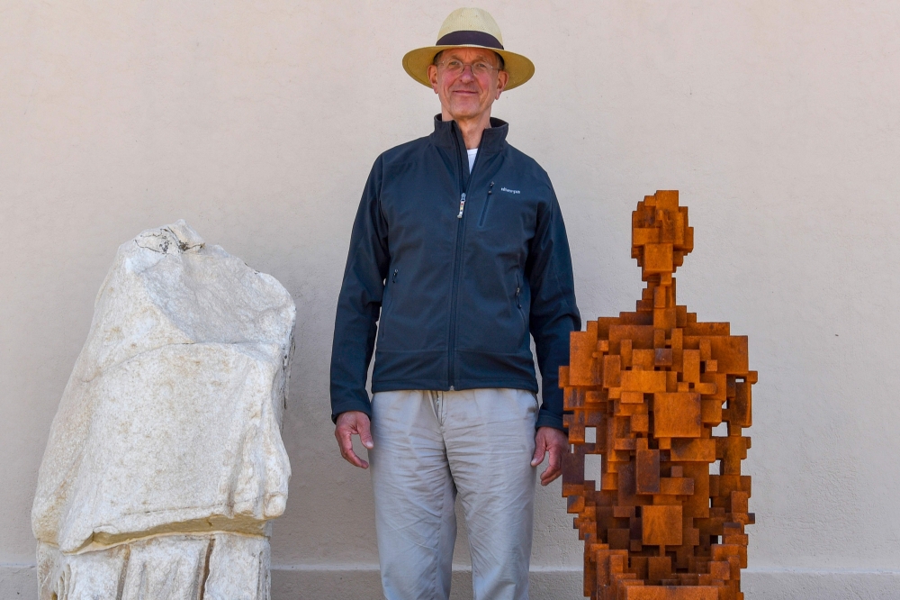 Renowned British artist Antony Gormley poses next to his sculpture called 