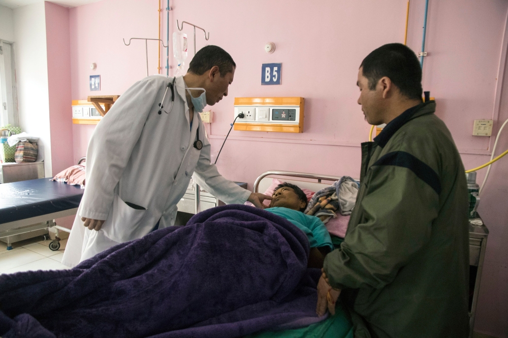 In this photo taken on March 30, 2019, Bhutan's Prime Minister Lotay Tshering (L) treats a patient at the National Referral Hospital in the Bhutanese capital Thimphu. AFP / Upasana Dahal
