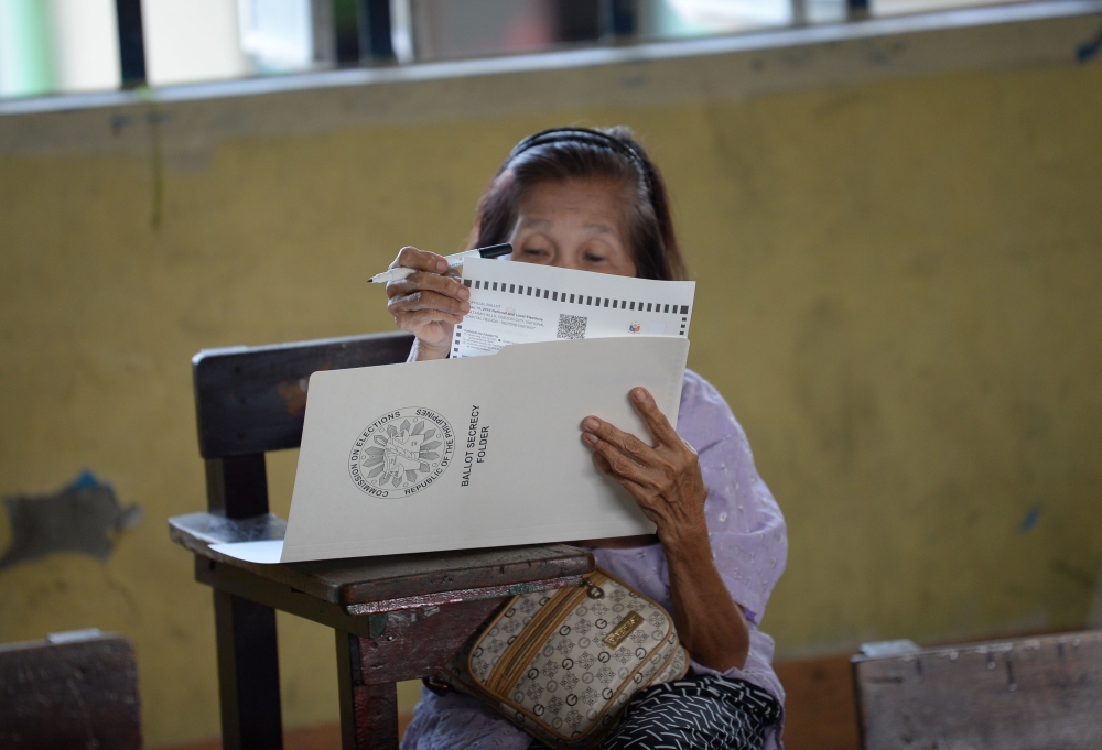 An elderly woman casts her vote for the mid-term elections at a polling precinct in Manila on May 13, 2019. AFP / TED ALJIBE