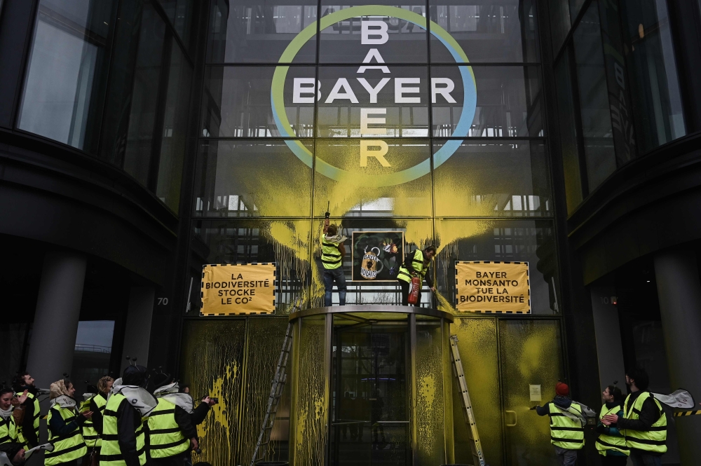 Activists stage a flash protest organised by the international movement 'Attac' at the offices of Bayer -which recently acquired Monsanto- in La Garenne Colombes near the financial district of La Defence on the outskirts of Paris on March 14, 2019. AFP/ P