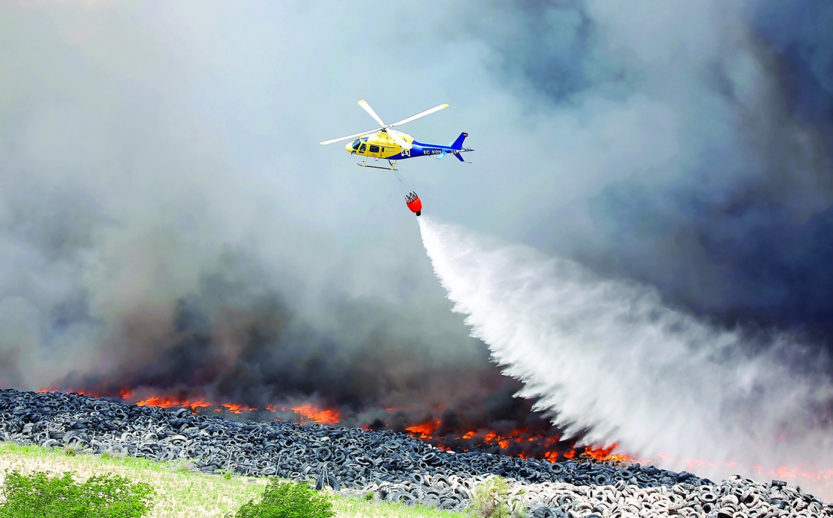 An helicopter throws water over a fire at a tire dump near a residential development in Sesena south of Madrid, May 13, 2016 Reuters/Sergio Perez