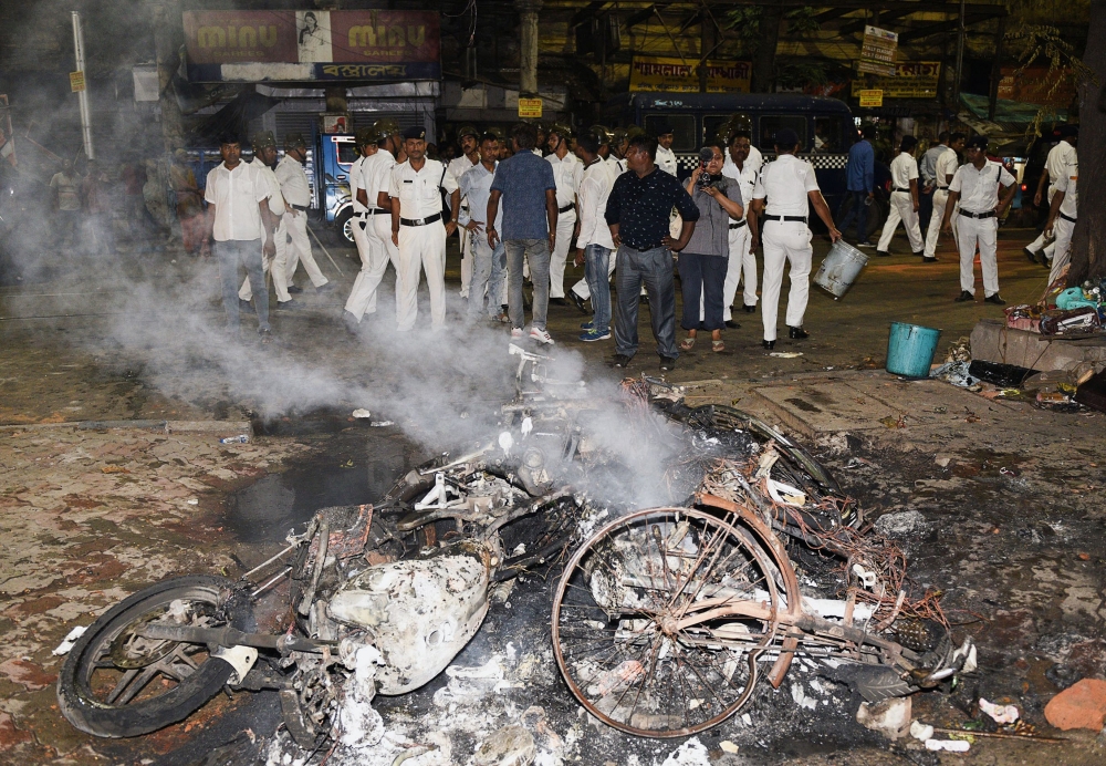 In this photo taken on May 14, 2019 Indian police stand next to burning debris on a street following clashes by rival groups during a campaign rally event held by Amit Shah, president of the ruling Bharatiya Janata Party (BJP), in Kolkata. (AFP)