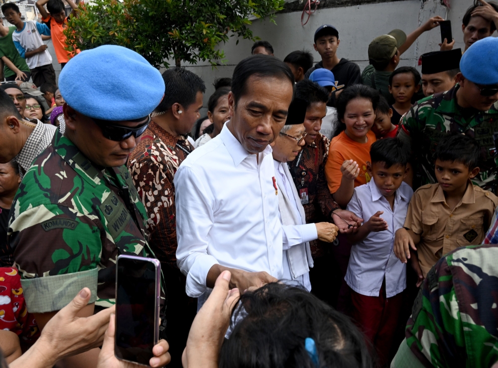 Indonesian President Joko Widodo (C) and his running mate Ma'ruf Amin (center R) speak with residents in a neighbourhood in Jakarta on May 21, 2019.  AFP / Goh Chai Hin
 