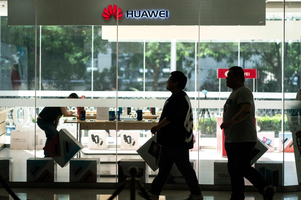 People walk past a Huawei retail store in Beijing on May 23, 2019.  AFP / FRED DUFOUR