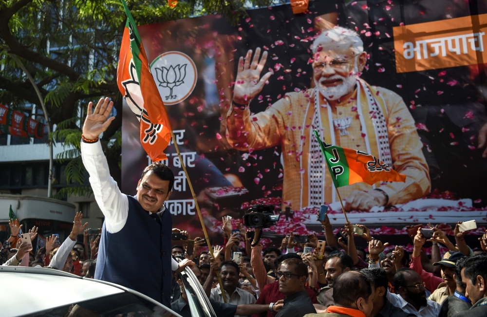 Maharastra state's Chief Minister Devendra Fadnavis waves towards supporters of Indian Prime Minister Narendra Modi and his ruling Bharatiya Janata Party (BJP) as they celebrate on the election results day outside the BJP headquarters in Mumbai on May 23,