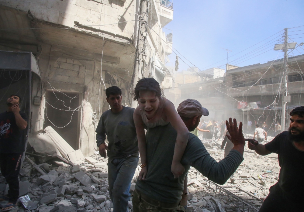 A man evacuates a young bombing casualty after a reported air strike by regime forces and their allies in the jihadist-held Syrian town of Maaret Al-Noman in the southern Idlib province, on May 26, 2019. / AFP / Abd el-Aziz Qitaz