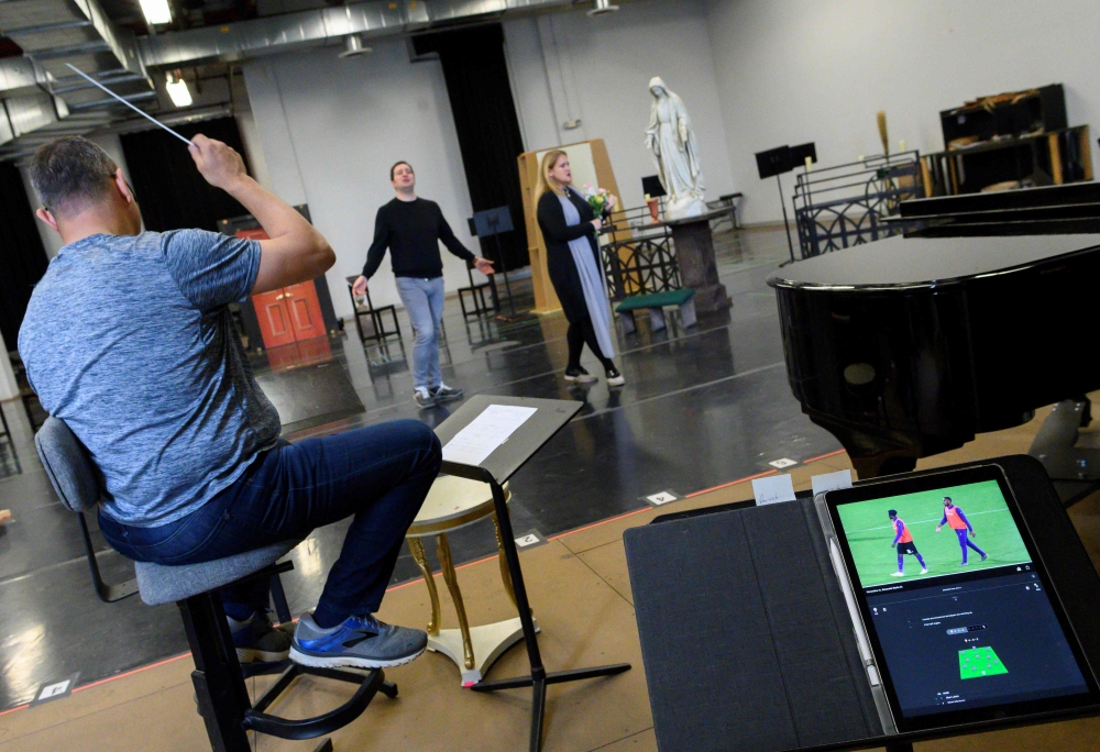A soccer match is played as Riccardo Massi (L) and Keri Alkema rehearse for the upcoming Washington National Opera (WNO) production of Tosca at WNO's Studio Workroom on April 29, 2019 in Washington, DC.  AFP / Andrew Caballero-Reynolds
 