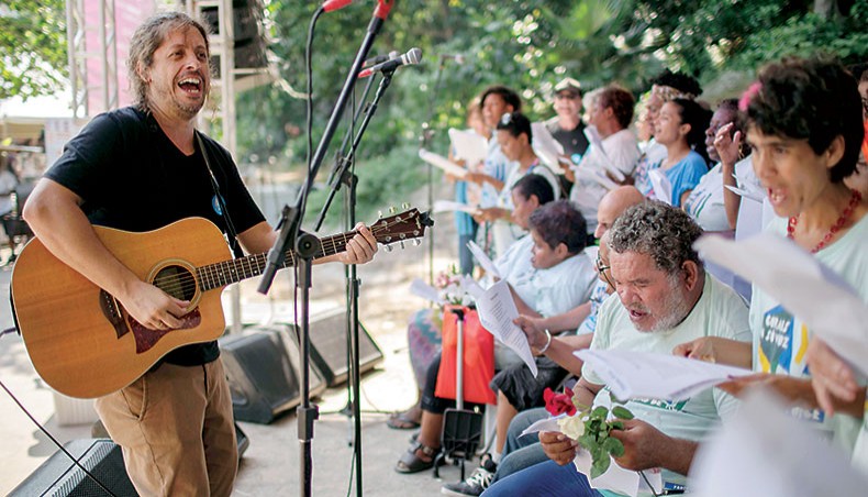 Brazilian musician Ricardo ‘Rico’ Branco de Vasconcelos (L), leads the ‘With One Voice’ choir performance during the Good Actions Day Fair organized by the NGO Atados at Garota de Ipanema Park in Rio de Janeiro on April 4, 2019. AFP