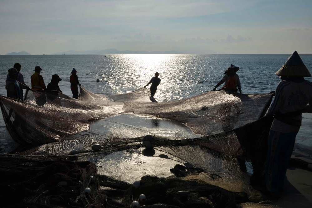 Fishermen carry their fishing nets along the shore in Banda Aceh on May 24, 2019. AFP / Chaideer Mahyuddin 