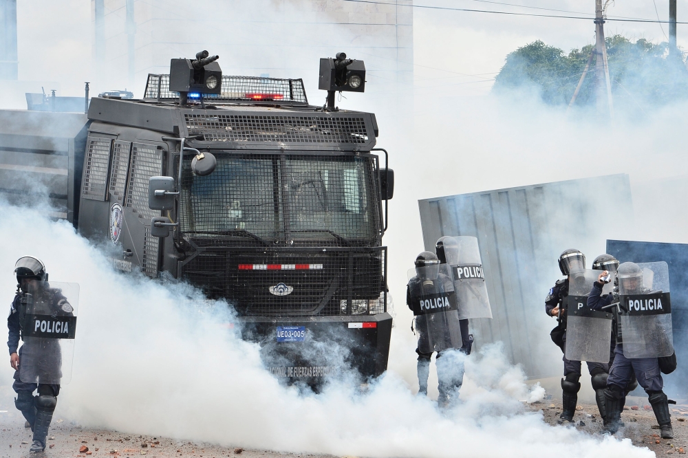 Riot police confront demonstrators during a protest in Tegucigalpa on May 30, 2019. Teachers' and medical doctors' unions joined by students protested against the privatisation of education and health and demand the resignation of Honduran President Juan 