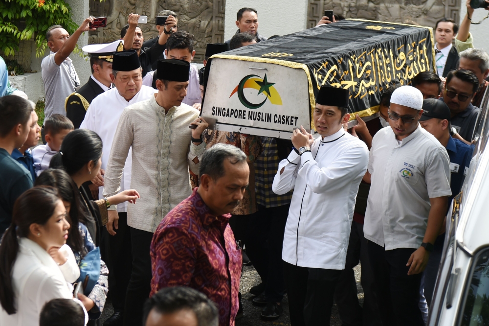 Former Indonesian President Susilo Bambang Yudhoyono (left in white) walks next to a casket carrying his wife Ani Yudhoyono, who passed away in Singapore on June 1, 2019. / AFP / ROSLAN RAHMAN