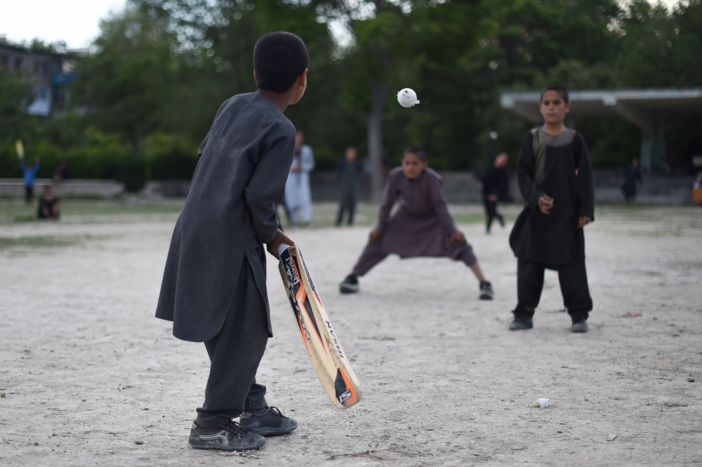 In this photo taken on May 19, 2019, Afghan children play cricket in a field in Kabul.   AFP / Wakil Kohsar
