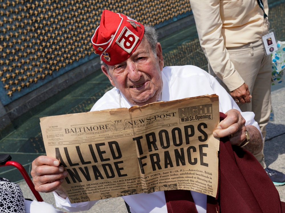 D-Day veteran and former POW Robert Levine, 94, of Teaneck, NJ, holds up a newspaper front page during the 75th anniversary of the D-Day landings in Normandy at the World War II Memorial in Washington, U.S., June 6, 2019. Reuters/Kevin Lamarque