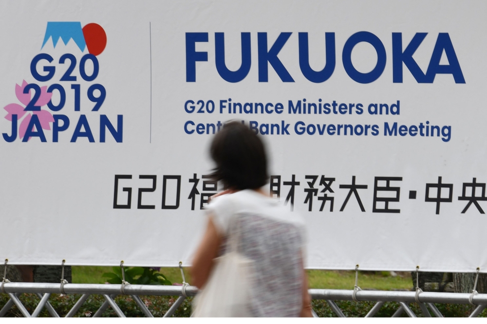 A woman walks past a banner for the upcoming G20 Finance Ministers and Central Bank Governors meeting in Fukuoka on June 7, 2019. / AFP / Toshifumi KITAMURA