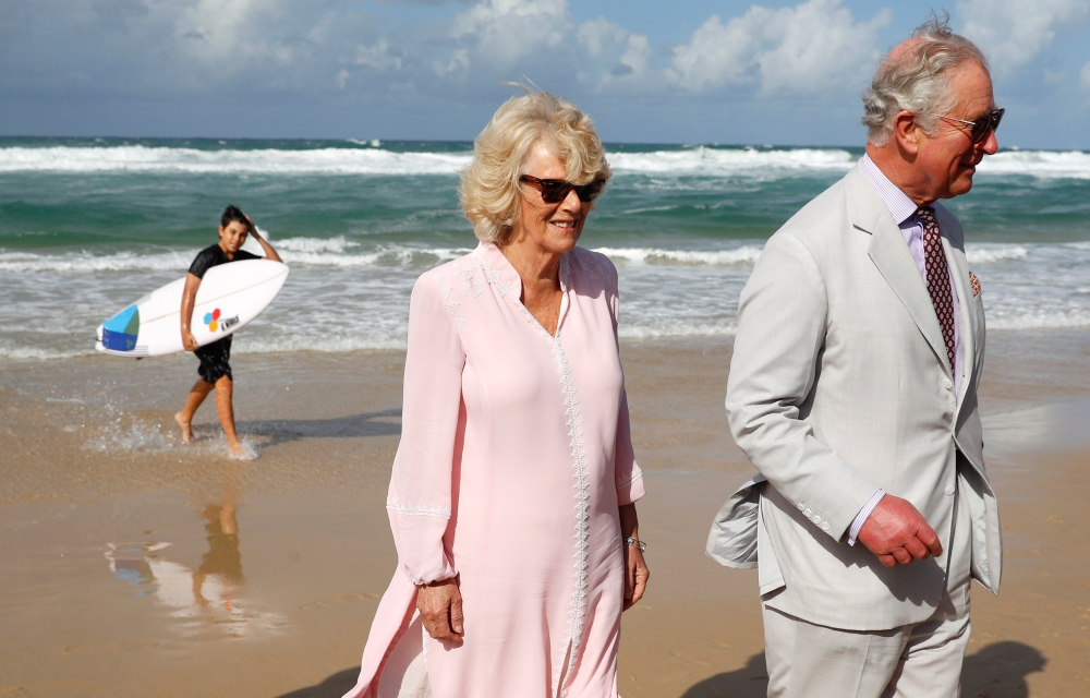 A surfer walks past as Prince Charles and Camilla, Duchess of Cornwall, visit Broadbeach, Australia, April 5, 2018. Reuters/Phil Noble