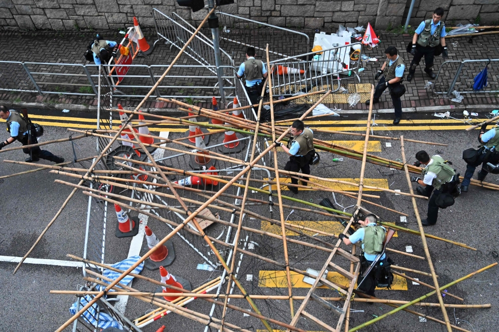 Police officers dissolve the barricades placed by demonstrators in Hong Kong on June 13, 2019. AFP / Hector Retamal 