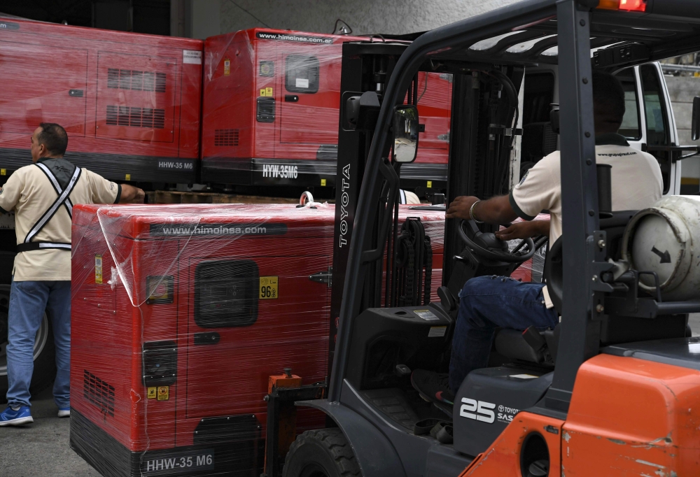 A worker unloads generators received as part of humanitarian aid through the Venezuelan Red Cross in Caracas, Venezuela on June 17, 2019. / AFP / YURI CORTEZ