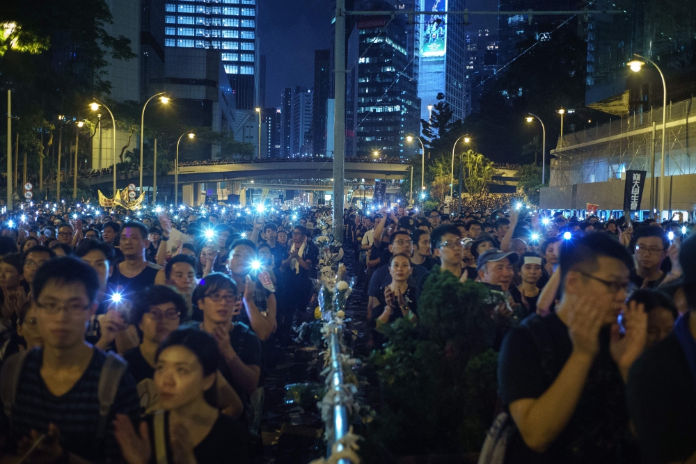 Protesters hold up their phones with lights on during a mass rally to protest against a controversial extradition bill that would allow suspected criminals to be sent to mainland China for trial.  AFP / Yan ZHAO
