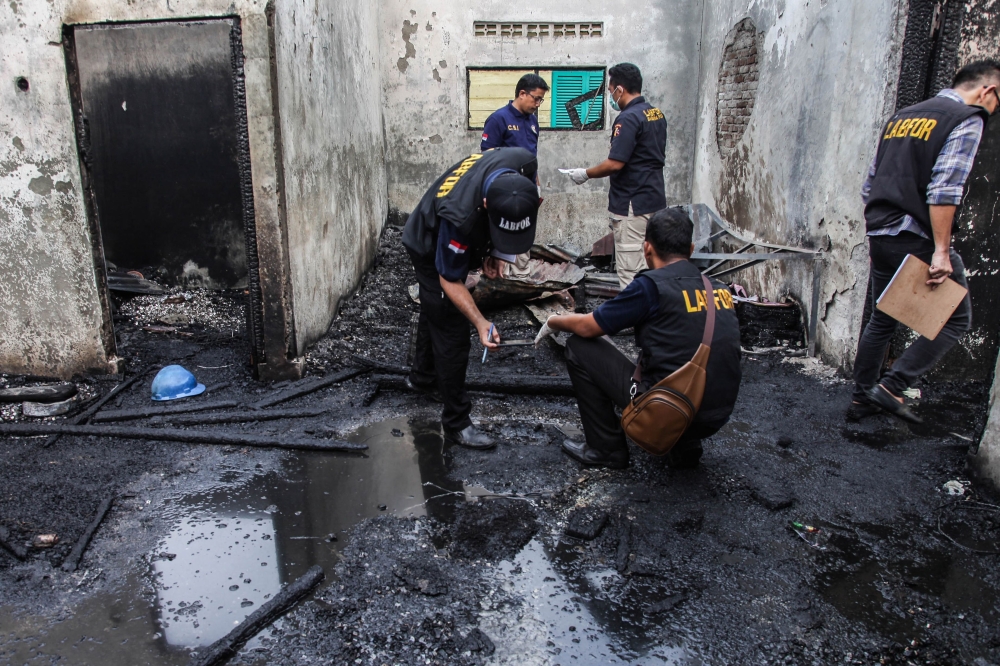 Investigators work on the scene of a burnt-out house that doubled as a matchstick factory in Binjai on June 21, 2019, following a fire on the premises that killed at least 30. AFP / Ivan Damanik 