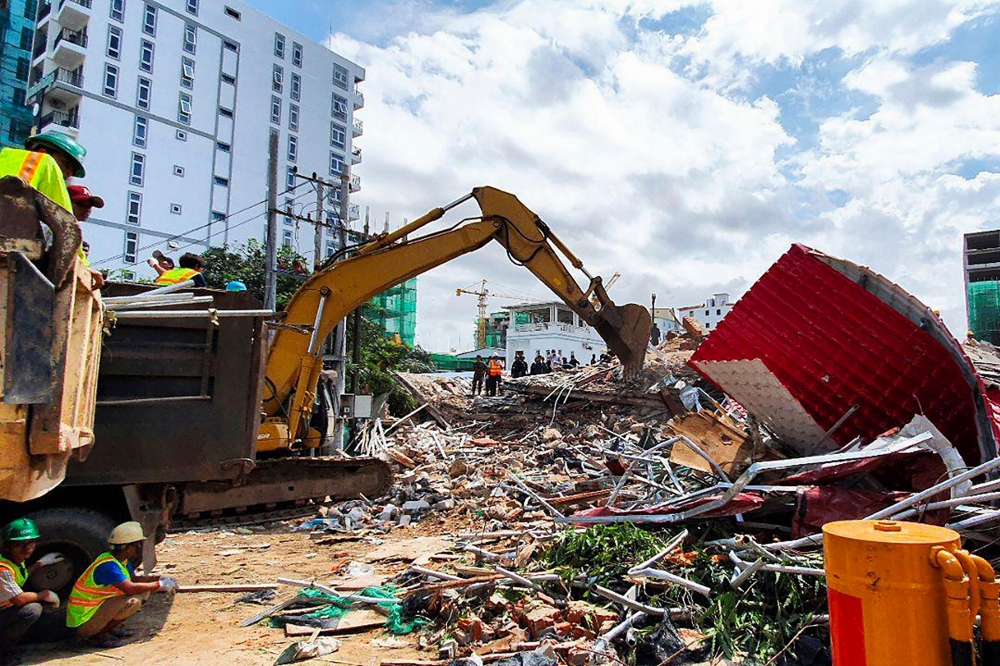 Rescue workers use an earthmover to clear debris after an under-construction building collapsed in Sihanoukville on June 22, 2019. / AFP / Ly LAY 