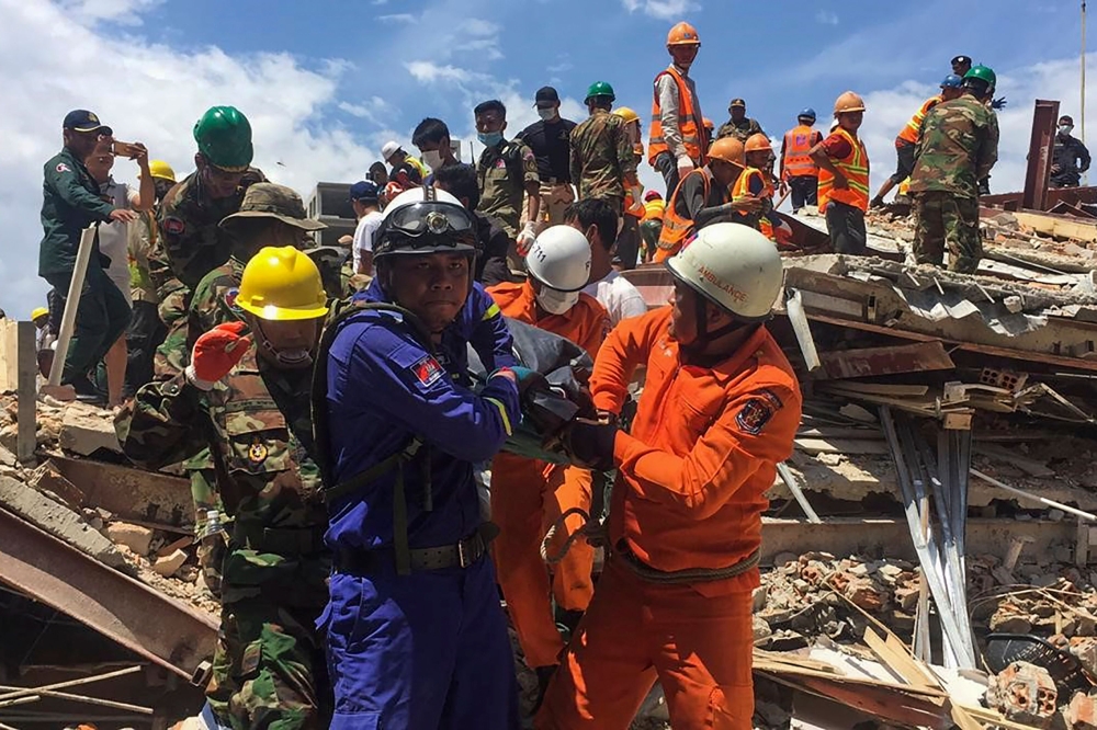 Rescue workers remove a victim from the debris after an under-construction building collapsed in Sihanoukville on June 22, 2019.  / AFP / Den AYUTHYEA 