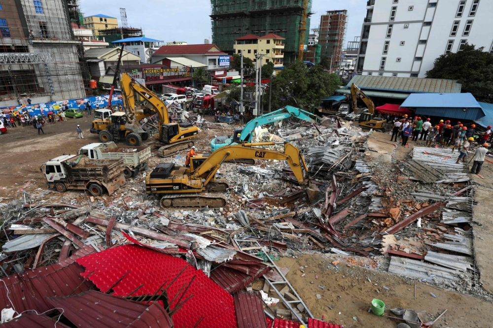 Rescue workers use earthmovers to clear debris as they search for victims a day after an under-construction building collapsed in Sihanoukville on June 23, 2019. AFP / Sun Rethy Kun