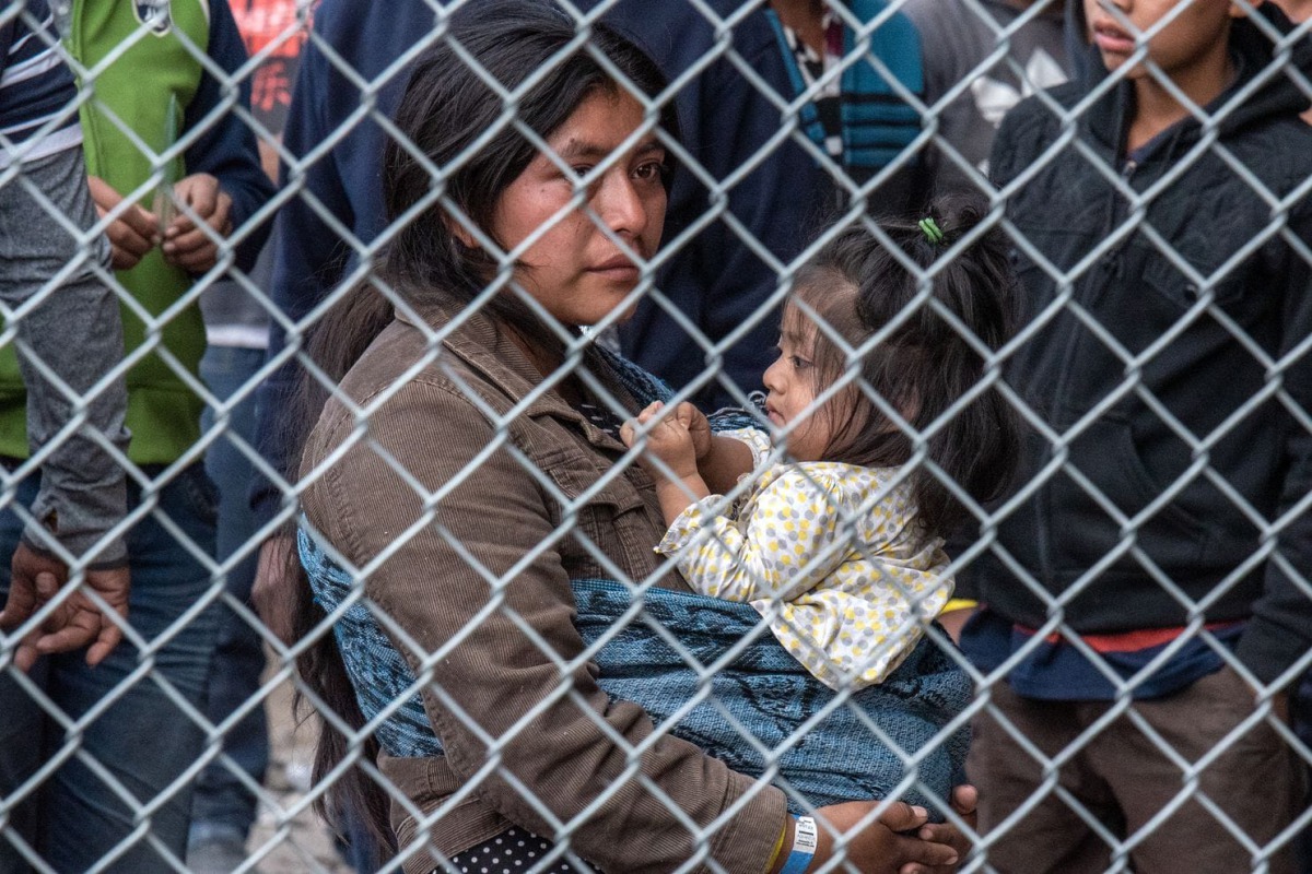 Migrants are gathered inside the fence of a makeshift detention center in El Paso on March 27. 