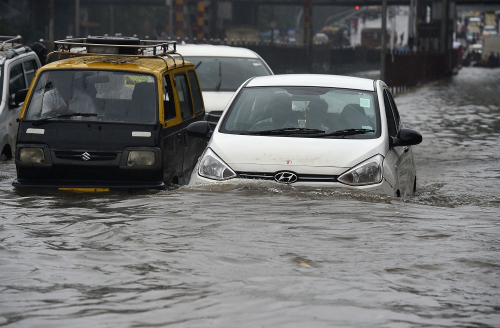 Vehicles drive along a flooded street after heavy rain showers in Mumbai on July 1, 2019. / AFP / PUNIT PARANJPE 