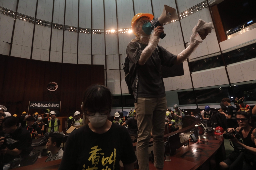 A protester uses a loudspeaker after they broke into the parliament chamber of the government headquarters in Hong Kong on July 1, 2019, on the 22nd anniversary of the city's handover from Britain to China. (AFP / VIVEK PRAKASH)