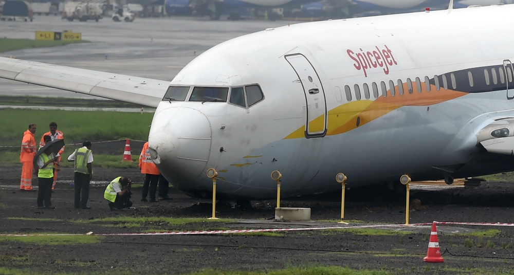 A SpiceJet aircraft is surrounded by airport staff as it stands stranded off the tarmac at Chhatrapati Shivaji Maharaj International Airport in Mumbai on July 2, 2019, after it overran the runway while landing during heavy rain, causing no injuries. / AFP
