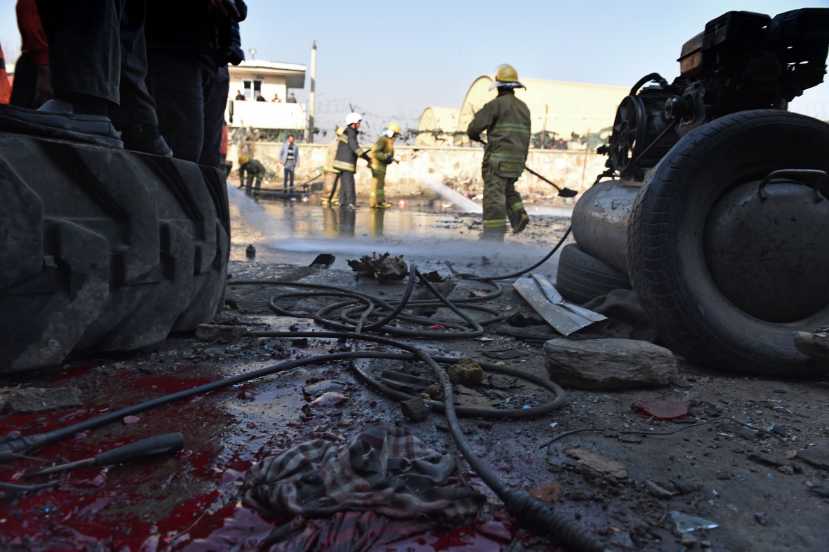 Afghan firefighters washing a road at the site of a suicide car bomb perpetrated by a Taliban bomber near the international airport in Kabul on December 27, 2015. AFP/Shah Marai