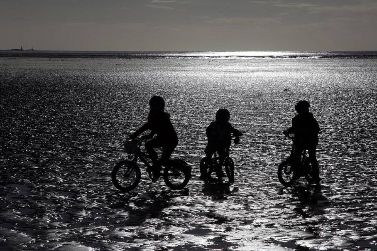 Children ride their bike along the beach during low tide near St Helier, Jersey, November 11, 2012. Reuters/Stefan Wermuth