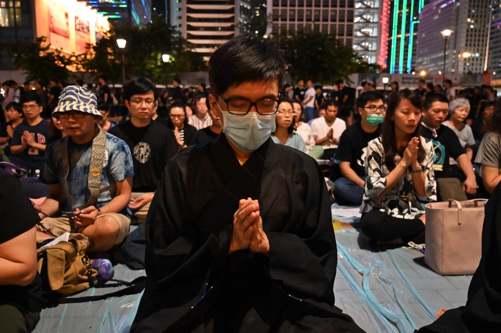 People offer prayers during a vigil in Hong Kong on July 6, 2019, in memory for four youths who had taken their lives in recent weeks as Hong Kong is rocked by anti-government protests. (AFP / HECTOR RETAMAL)