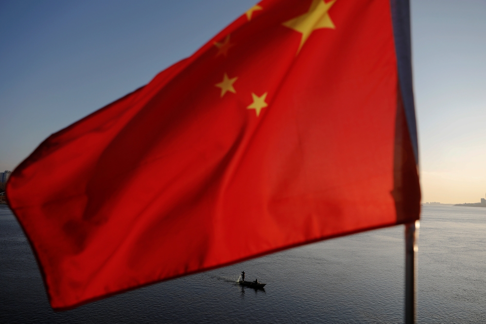 N Korean fishermen are seen as a Chinese flag flutters from the Broken Bridge as the sun sets over Yalu River between N Korean town of Sinuiju Dandong in Liaoning Province, China, Nov 19, 2017. Reuters/Damir Sagolj