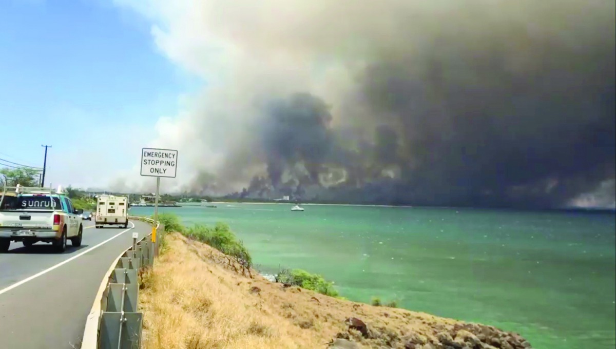 A plume of smoke spreads across the sky during a wildfire in Kihei, as vehicles move along a road in Maui, Hawaii, in this still image taken from a July 11, 2019 video from social media. Traci Teel Szymanski/via Reuters