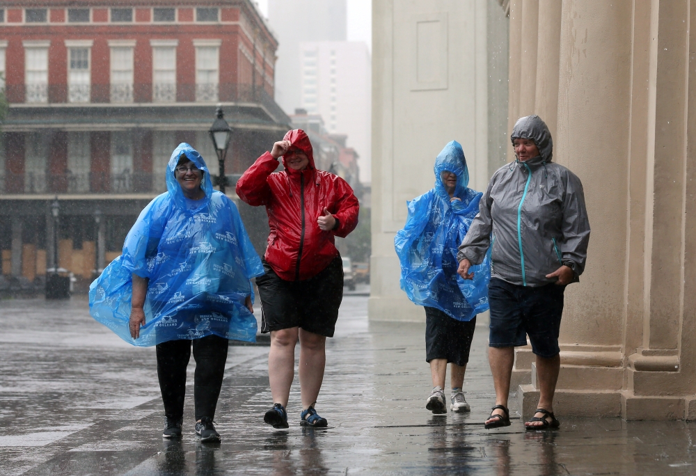 Tourists walk through rain in the French Quarter caused by Hurricane Barry in New Orleans, Louisiana, U.S. July 13, 2019. (REUTERS/Jonathan Bachman)
