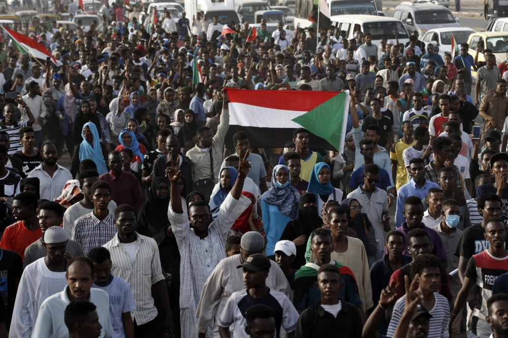 Sudanese protesters raise national flags as they rally in the capital Khartoum to mourn dozens of demonstrators killed last month in a brutal raid on a Khartoum sit-in, on July 13, 2019.(AFP / ASHRAF SHAZLY)