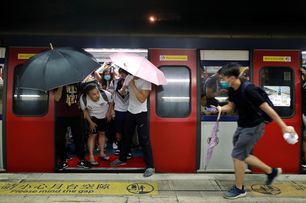 Protesters stop the door of a Mass Transit Railway (MTR) subway from closing to allow more protesters to board the train to retreat after a clash with police at a shopping mall, in Hong Kong, China July 14, 2019. Reuters/Tyrone Siu
 