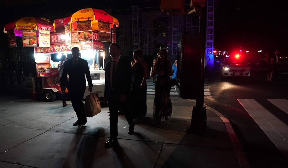 People walk down the streets during a major power outage affecting parts of New York City on July 13, 2019.  AFP / Timothy A Clary 