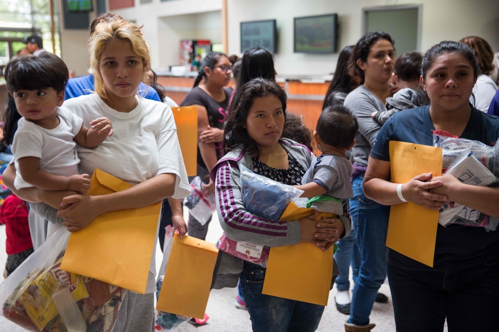 Immigrants wait to head to a nearby relief center after being dropped off at a bus station shortly after release from detention in McAllen, Texas on June 17, 2018. AFP/Loren Elliott