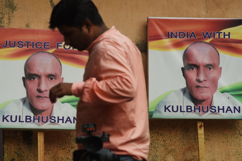 An Indian resident walks past placards with the picture of Kulbhushan Jadhav, an Indian national convicted of spying in Pakistan, in the neighborhood where he grew up, in Mumbai on July 17, 2019. AFP / Indranil Mukherjee 