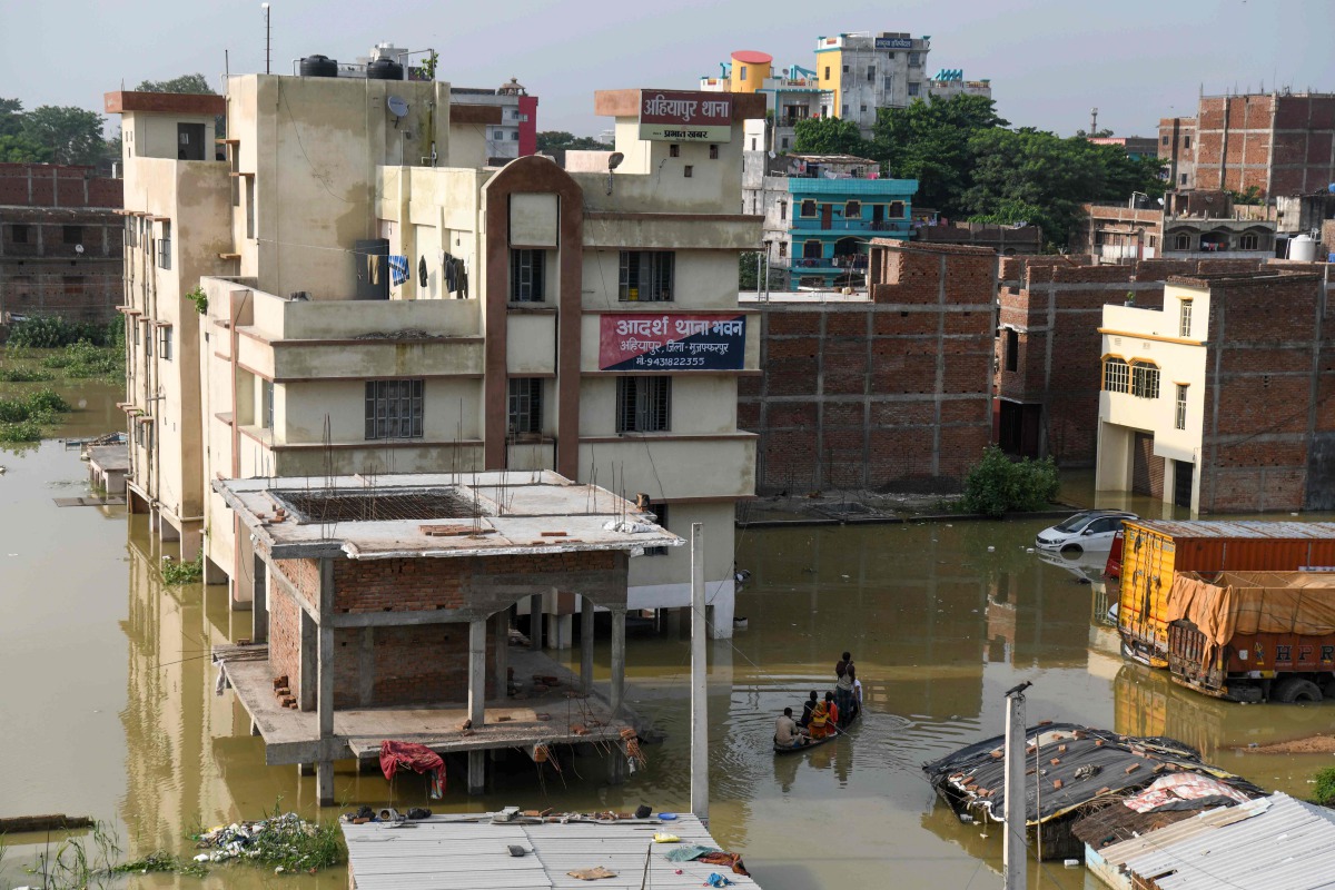 An Indian policeman travels with residents on a wooden boat to cross a flooded locality near the Ahiyapur police station at Muzaffarpur district in the Indian state of Bihar on July 18, 2019. AFP / Sachin Kumar