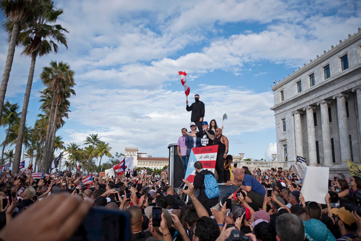 Puerto Rican rapper Rene Perez, aka Residente, (C) speaks alongside Puerto Rican reggaeton singer Bad Bunny (top) and Puerto Rican actor Benicio del Toro as they take part of a demonstration demanding Governor Ricardo Rossello's resignation in San Juan, P