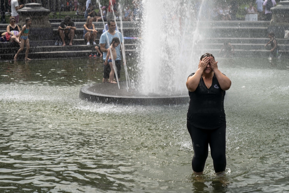A woman cools off in the fountain at Washington Square Park during a hot afternoon day on July 17, 2019 in New York City. Drew Angerer/Getty Images/AFP
