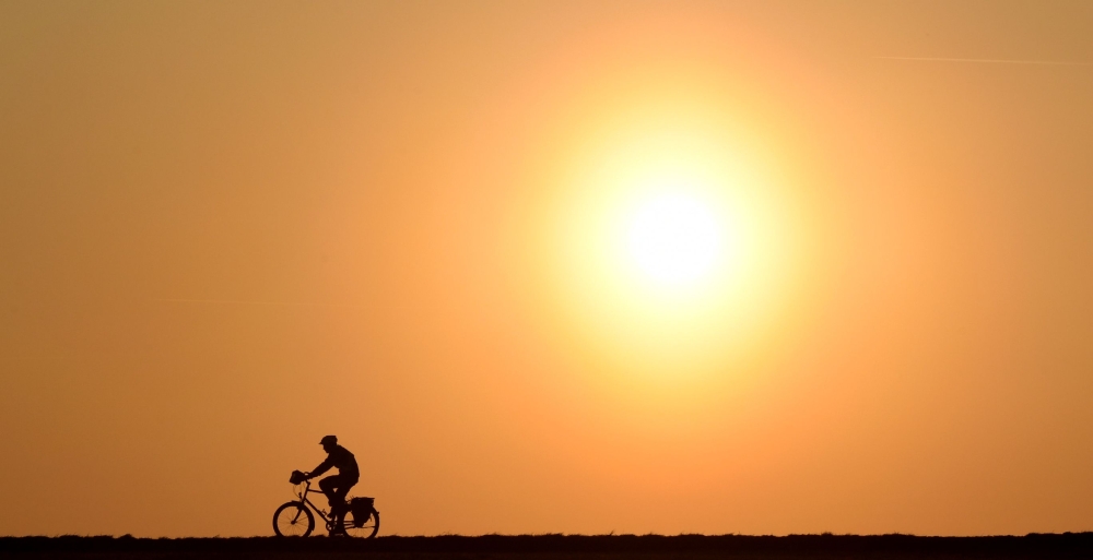 A cyclist passes a street near the village of Pflaumdorf, southern Germany, during sunset on February 28, 2019. AFP/Christof Stache