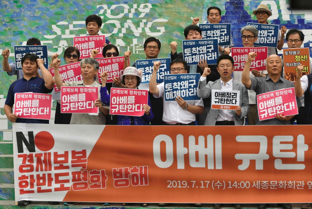 South Korean protesters holding placards reading 