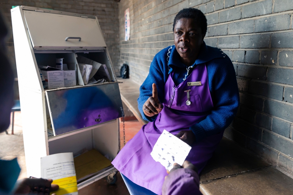 Nurse Angela Chikondo instructs Blessing Chingwaru, 29, an HIV positive TB patient on how he should take medication received as part of his treatment at Rutsanana Polyclinic in Glen Norah township, Harare June 24, 2019. AFP / Jekesai Njikizana 
