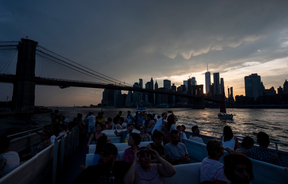 People sit on a ferry while the sun sets behind the skyline of Lower Manhattan on July 21, 2019 in New York City. An oppressive heat wave stretching from the Midwestern plains to the Atlantic coast had nearly 150 million people struggling to stay cool in 