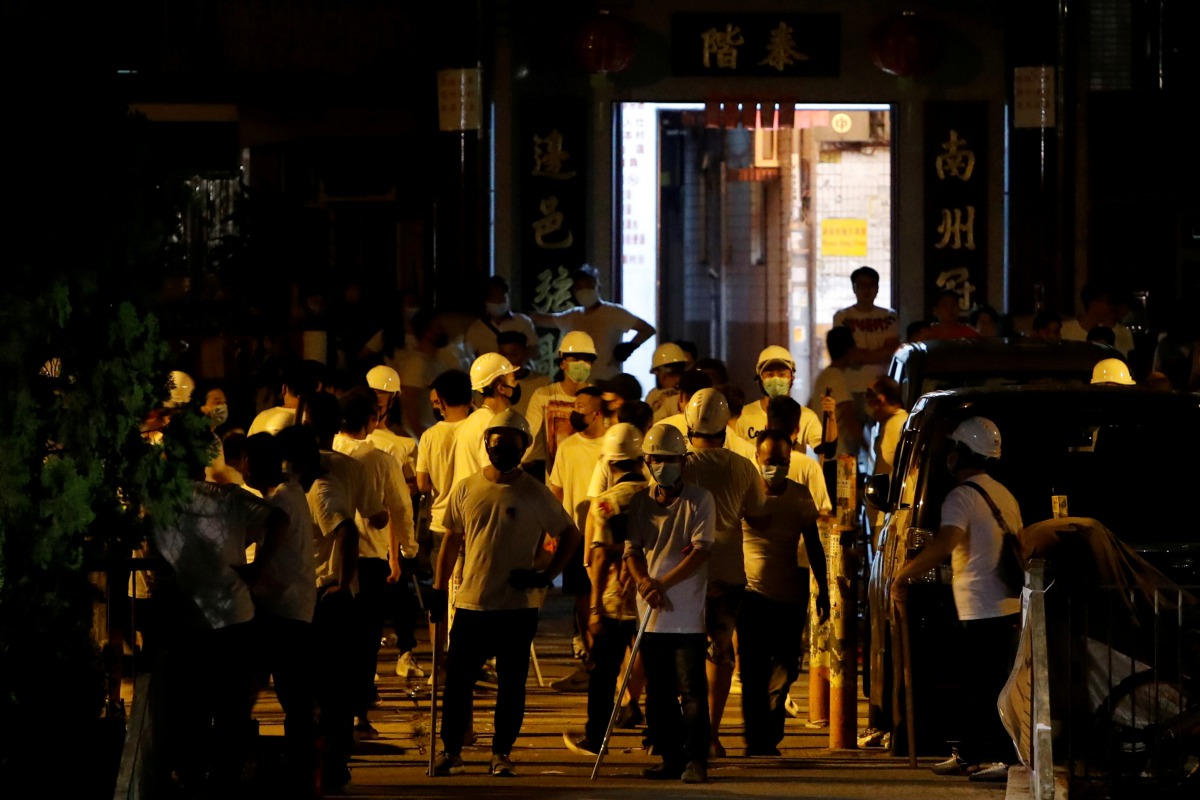 Men in white T-shirts and carrying poles are seen in Yuen Long after attacking anti-extradition bill demonstrators at a train station in Hong Kong, China, July 22, 2019. Reuters/Tyrone Siu